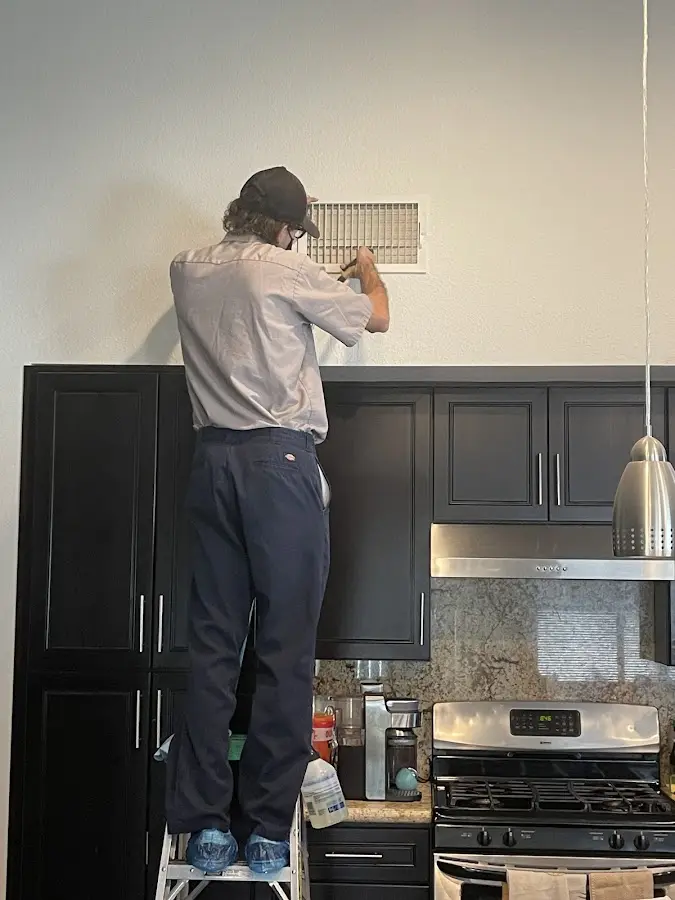 Technician inspecting an air vent during HVAC service in Castro Valley